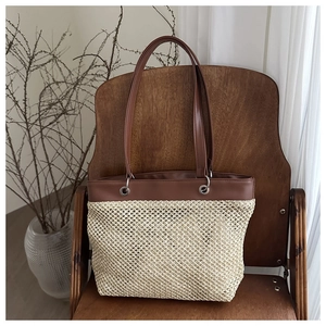 Close-up of straw woven tote with brown leather trim and silver ring hardware