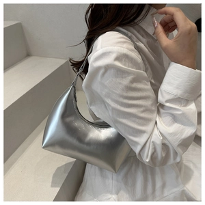 Détail d'un sac demi-lune argenté métallisé au fini brillant sur fond minimaliste