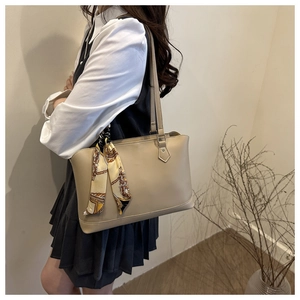 Detail of elegant beige tote bag with decorative silk scarf and leather fasteners