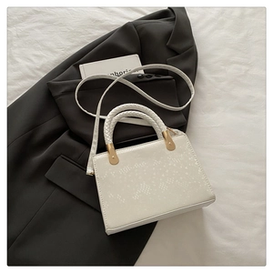 Macro detail of white stone pattern handbag with woven handles and gold hardware