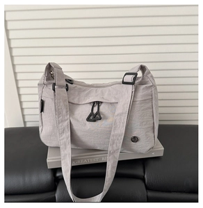 Dettaglio della borsa a tracolla in nylon grigio impermeabile con logo e motivo orb