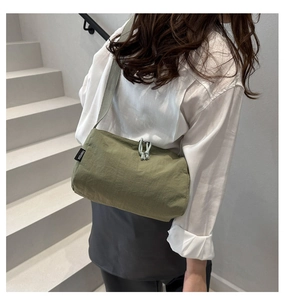 Detail of olive green nylon crossbody bag showing branded label and drawstring knot