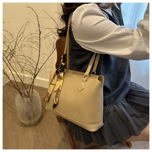Close-up of beige leather tote bag with silk scarf handle detail and brown floral patterns