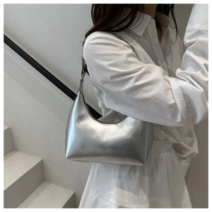 Détail d'un sac hobo argenté brillant avec design en croissant et finition miroir chic