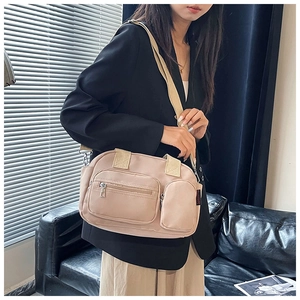 Détail du sac à bandoulière en nylon beige avec plusieurs poches et sangle en tissu large