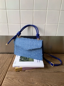 Détail du sac à main en denim bleu clair avec texture touffetée 3D et accents dorés
