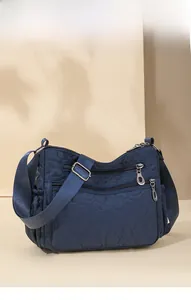 Close-up of heart-quilted nylon crossbody bag with functional multiple zipper pockets