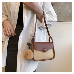 Detail of retro color-block shoulder bag with a round button and plush ball charm