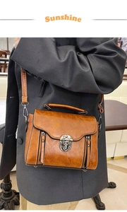 Brown vintage messenger bag with metal turn-lock and adjustable strap on grey blazer