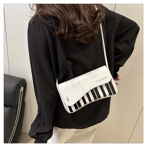 Détail d'un sac à bandoulière en PU blanc avec touches de piano et motifs de notes de musique