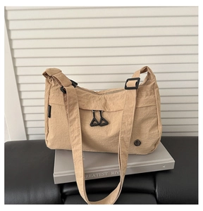 Dettaglio borsa a tracolla in nylon marrone chiaro con doppia zip e logo in metallo