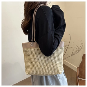 Detail of summer straw tote bag with premium khaki leather trim on a shoulder model