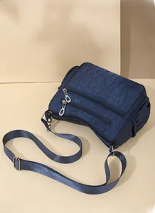 Detail of dark blue crossbody bag featuring heart-embossed fabric and multiple zippers