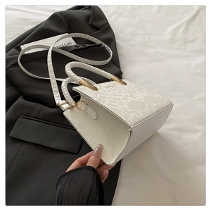White snakeskin textured handbag with woven handle and gold hardware on black blazer