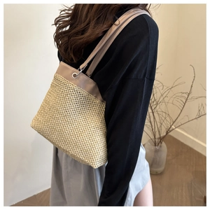 Detail of straw woven tote with leather trim and metal ring shoulder strap attachment