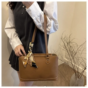 Close-up of brown faux leather tote with white stitching and floral scarf detail
