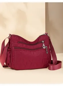 Detail of heart quilting texture and double silver zippers on burgundy nylon shoulder bag