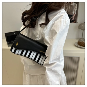 Détail du motif touches de piano et imprimé I LIKE MUSIC sur le sac en cuir noir