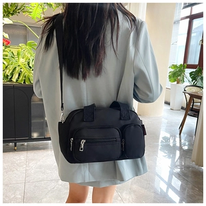 Détail du sac bandoulière noir multi-poches avec sangle en nylon porté par un mannequin