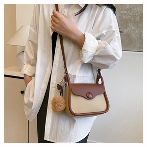 Detail of crossbody bag with beige and brown contrast design and plush charm