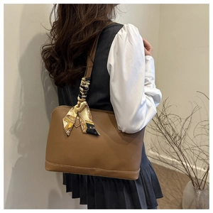 Side view of a brown leather tote bag with white stitching and decorative scarf detail