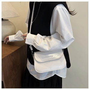 Detail van minimalistische witte leren crossbodytas met zilveren gespen en dunne riem