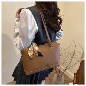 Brown faux leather tote bag with geometric silk scarf shown from a side-angle view