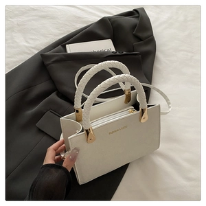 Detail of white stone texture crossbody bag with woven handles and golden fashion logo