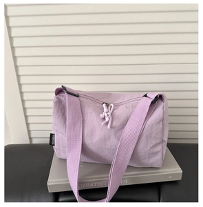 Close-up of light purple nylon barrel bag with woven brand label and rope zipper pull