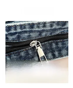 Detail of durable metal zipper closure on denim bag with neat yellow stitching