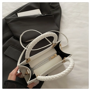 Detail of white stone-patterned crossbody bag with woven handle and golden hardware