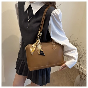 Close-up of brown leather tote bag with yellow printed silk scarf on shoulder strap
