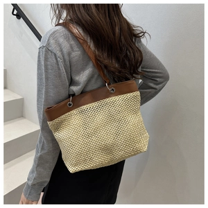 Detailed close-up of straw woven texture and brown leather strap on a summer tote bag