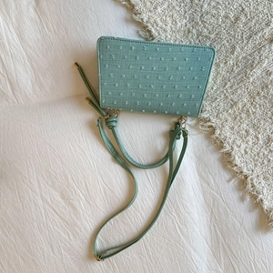 Détail du sac carré vert menthe montrant le tissu texturé avec des accents de pois 3D