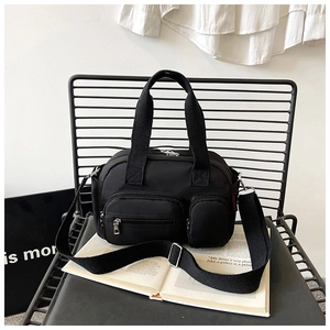 Détail d'un sac bandoulière en nylon noir avec trois poches zippées et poignées robustes