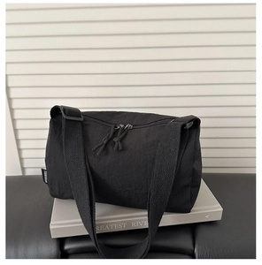 Detail of black nylon messenger bag with double zipper pulls and woven brand label