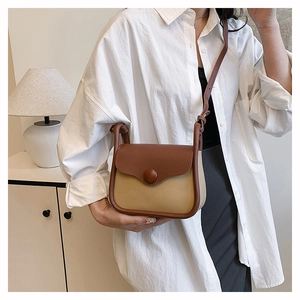 Detail of a minimalist two-tone crossbody bag with elegant brown and beige leather flap