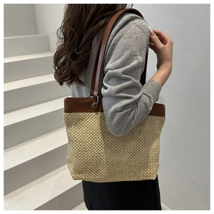 Detail of beige straw weave texture and brown leather strap on a summer tote bag