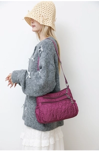 Detail of magenta quilted nylon shoulder bag with heart patterns and multi-pocket zippers