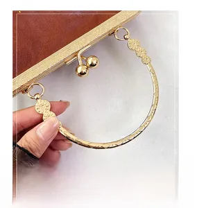 Dettaglio della borsa vintage in pelle marrone con manici in metallo dorato e motivi floreali