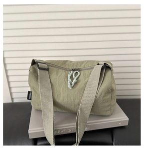 Detail view of olive green crossbody bag with brand label and knotted zipper pull