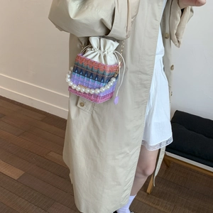 Handwoven drawstring bucket bag with colorful geometric patterns and pearl handle strap