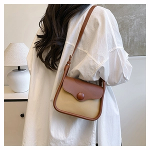 Close-up of retro color-block shoulder bag with cream leather and brown trim on a model