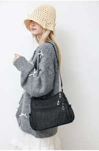 Close-up of black nylon shoulder bag with heart quilting and multi-zipper pockets