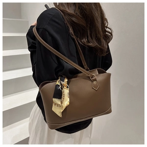 Detail of dark brown tote bag featuring matte leather texture and decorative silk scarf