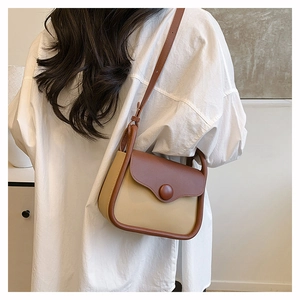 Detail showing contrast stitching and two-tone leather design on compact crossbody bag