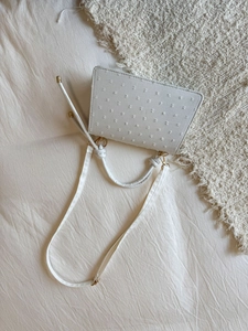 Détail d'un sac à main crème avec finitions dorées et texture à pois en relief chic