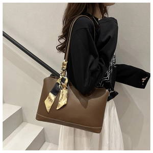 Detail of dark brown tote bag with decorative silk scarf on handle and contrast stitching