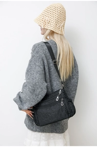 Detail of heart-quilted nylon crossbody bag with multiple zip pockets and adjustable strap