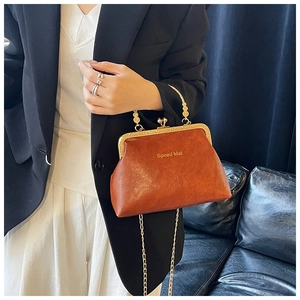 Dettaglio borsa vintage in pelle marrone con chiusura a scatto e catena dorata